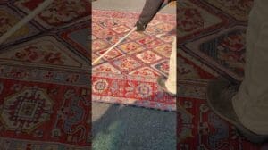 Luftstaubentfernung bei einem Soumak-Teppich, die meisten Flachgewebe-Wollteppiche halten nicht so viel Staub wie geschnittene Teppiche.